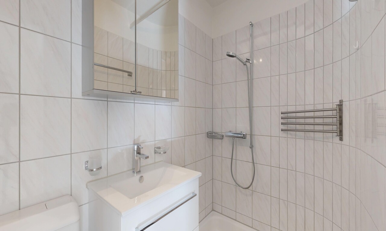 bathroom with vanity, a tile shower, tile walls, and a towel warming rack