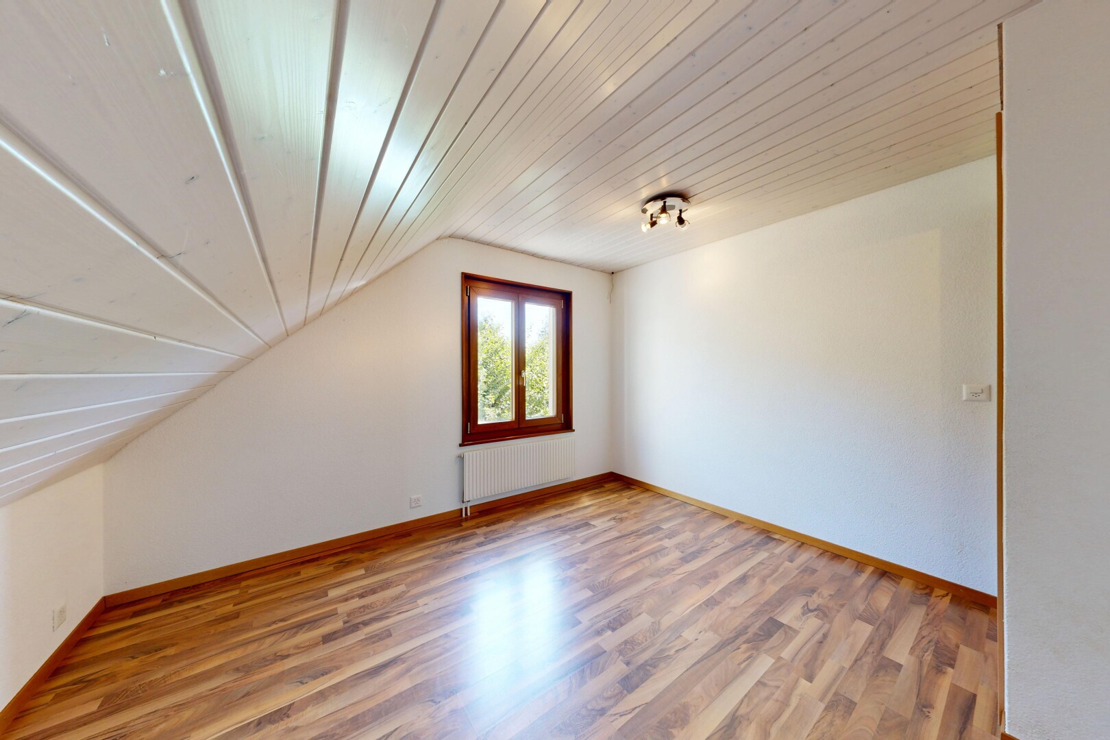 pièce vide avec sol en finition bois, wood finish floor, inside property, plafond voûté, et vaulted ceiling