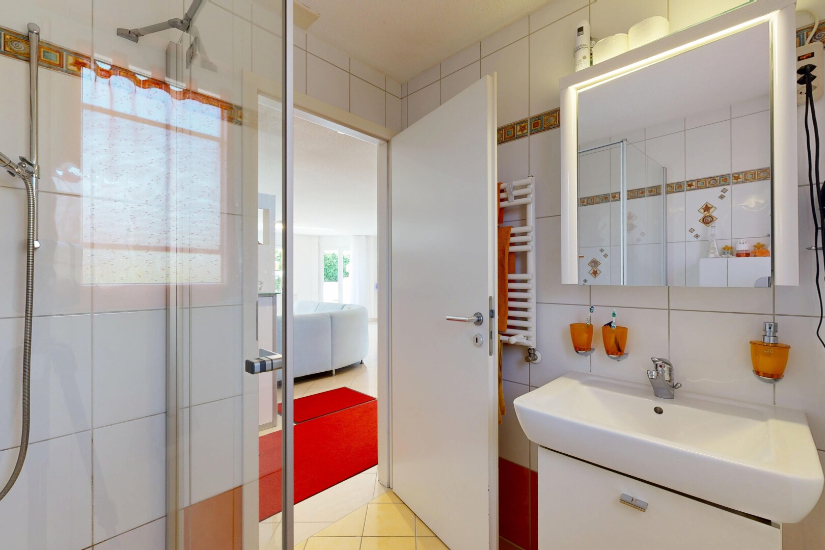salle de bains avec mur en carrelage, tile wall, miroir, douche, et light floor