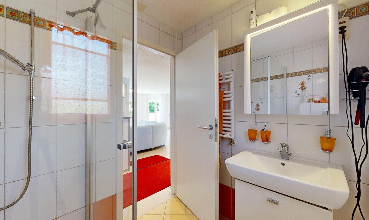 salle de bains avec mur en carrelage, tile wall, miroir, douche, et light floor