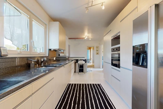 cuisine avec éclairage sur rail, réfrigérateur, dark countertops, light floor, et évier