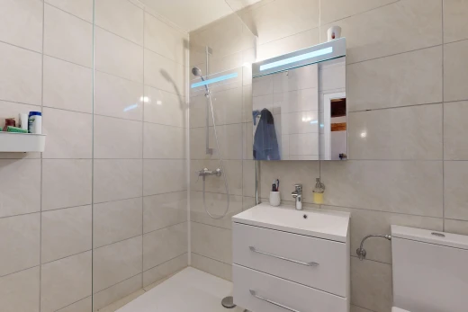 salle de bains avec douche, mur carrelé, vasque, miroir, et meuble-lavabo