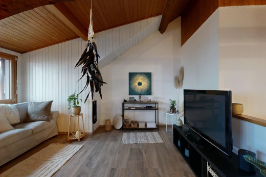 salon avec poutres apparentes, plafond voûté, télévision, et plafond de bois