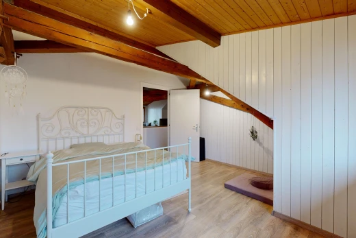 chambre avec plancher de bois, plafond voûté, mur en bois, poutres apparentes, et plafond de bois