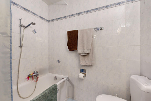 salle de bains avec douche, mur carrelé, et toilettes
