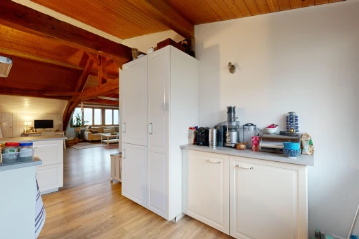 cuisine avec plan de travail, meubles blancs, espace à vivre ouvert, et plafond voûté