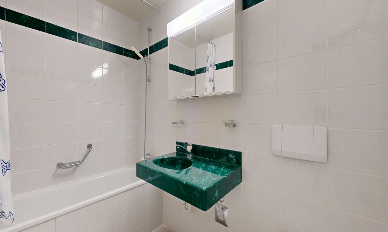 bathroom featuring tiled shower / bath combo, vanity, and tile walls