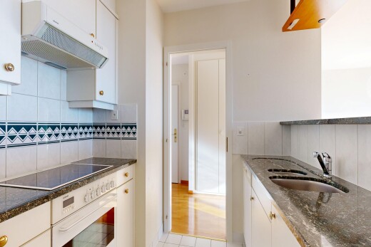 cuisine avec dark countertops, hotte, armoires blanches, white cabinets, et light floor