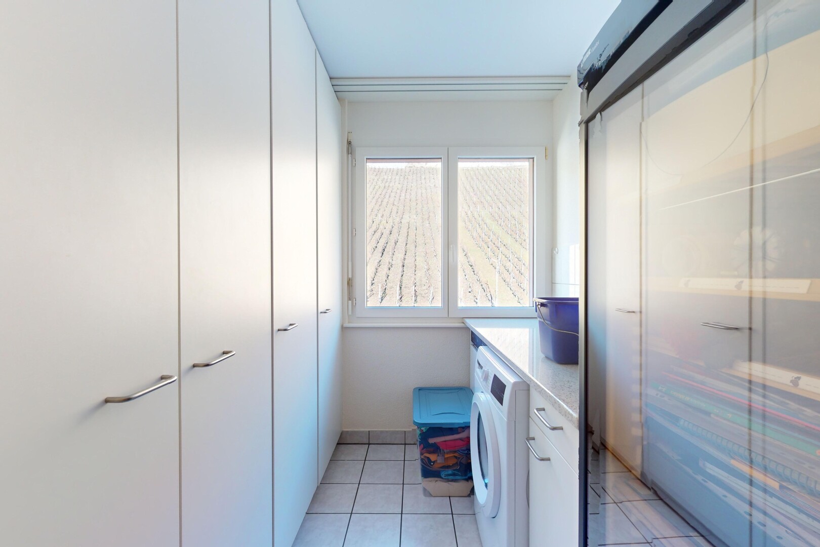 buanderie avec machine à laver / sèche-linge, lumière naturelle, et carrelage