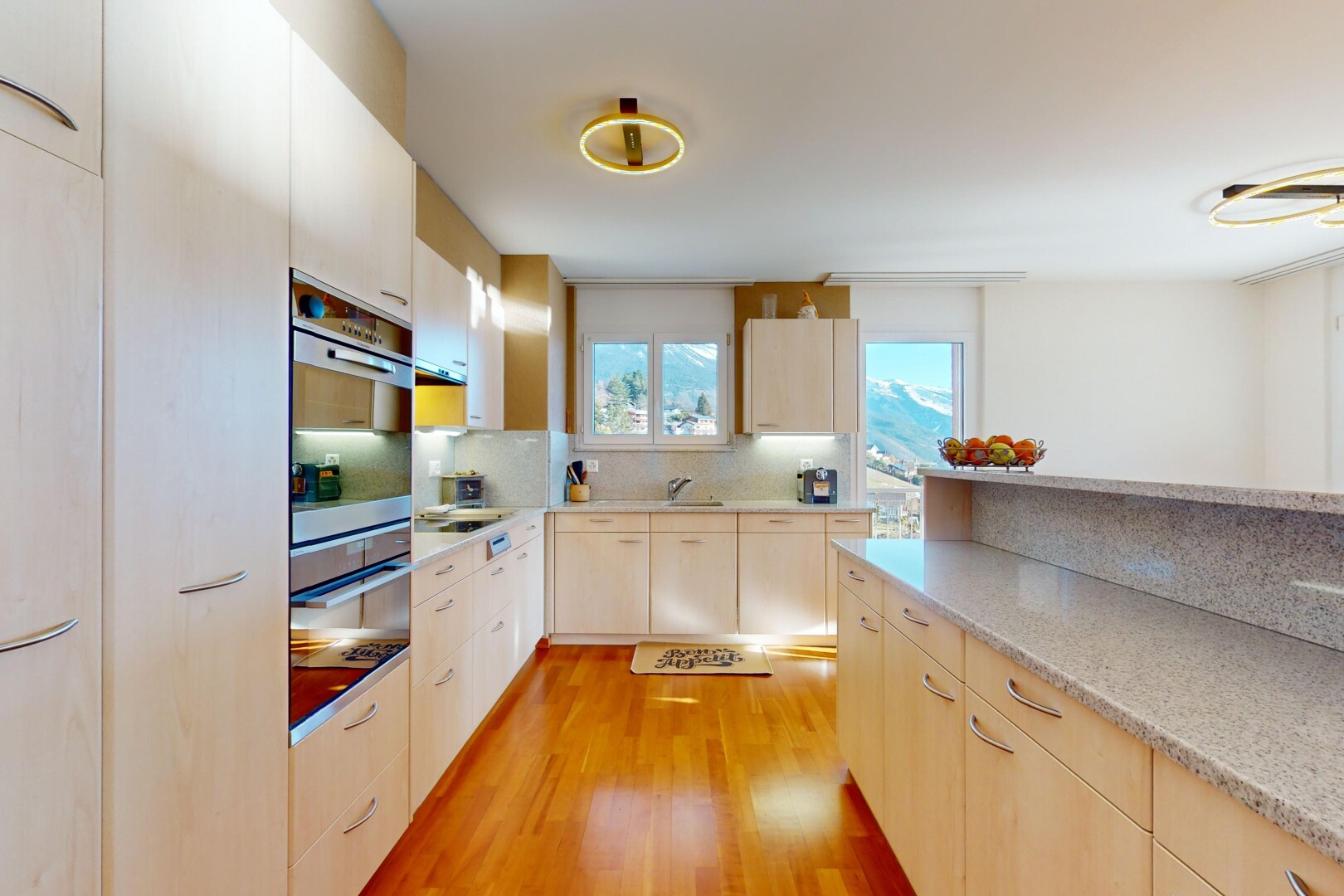 cuisine avec plancher de bois, crédence, four, plan de travail, et lumière naturelle