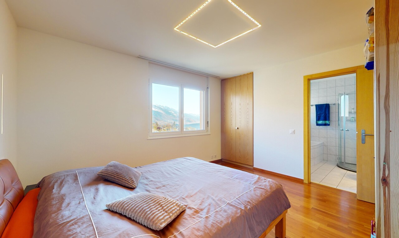 chambre avec salle de bains attenante, lumière naturelle, et plancher de bois