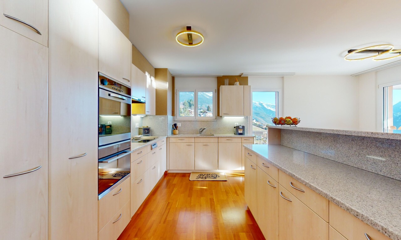 cuisine avec plancher de bois, crédence, four, plan de travail, et lumière naturelle