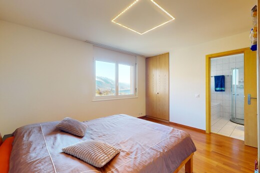 chambre avec salle de bains attenante, lumière naturelle, et plancher de bois