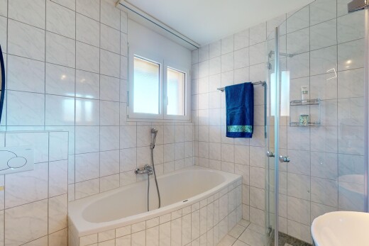 salle de bains avec douche, lumière naturelle, et mur carrelé