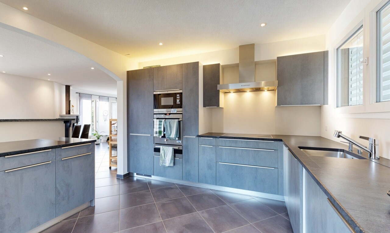 cuisine avec dark floor, hotte, dark countertops, lumière naturelle, et natural light