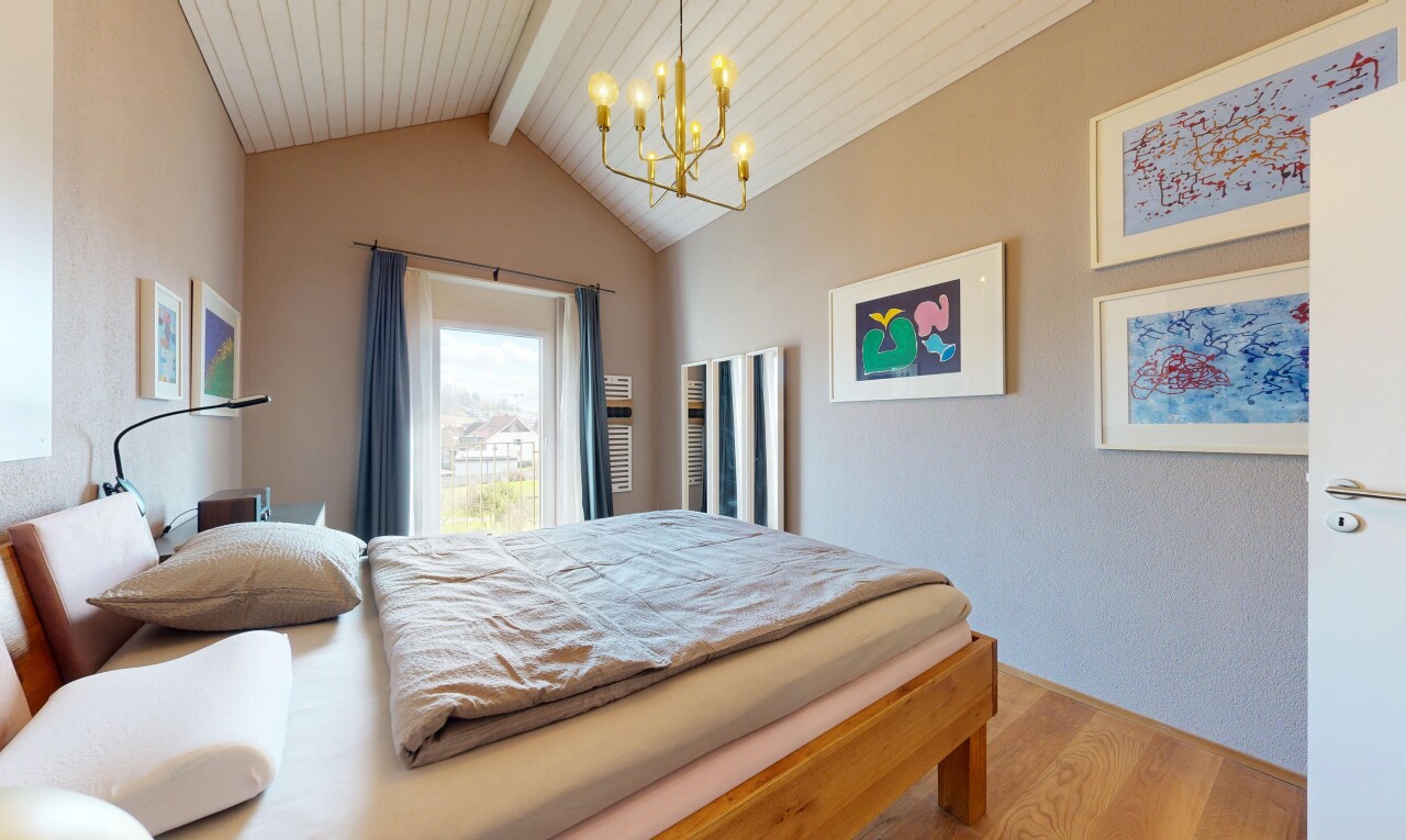 chambre avec lustre remarquable, sol en finition bois, wood finish floor, plafond à poutres, et beamed ceiling