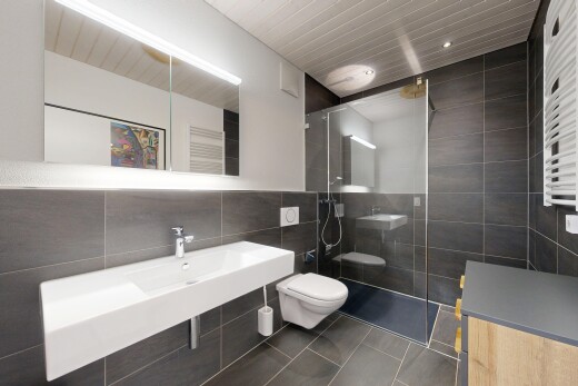 full bath with tile walls, a towel warmer, walk in shower, radiator heating unit, and dark tile patterned flooring