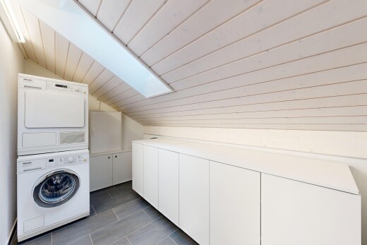laundry room featuring a skylight, cabinet space, a vaulted wood ceiling, and stacked washer / drying machine