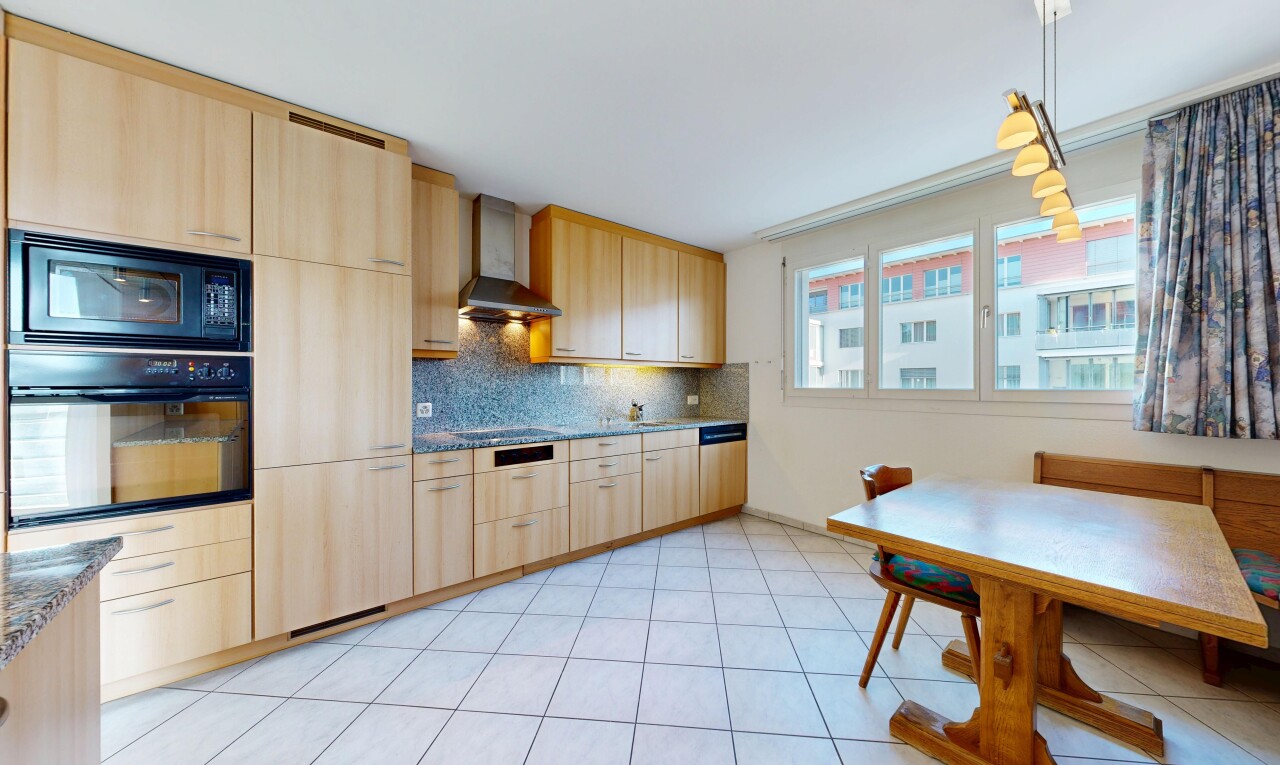 kitchen featuring light wood finish cabinets, black appliances, and pendant lighting