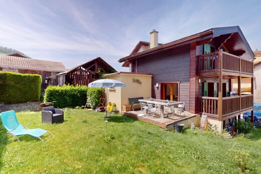outdoor house with a balcony, a lawn, and a chimney