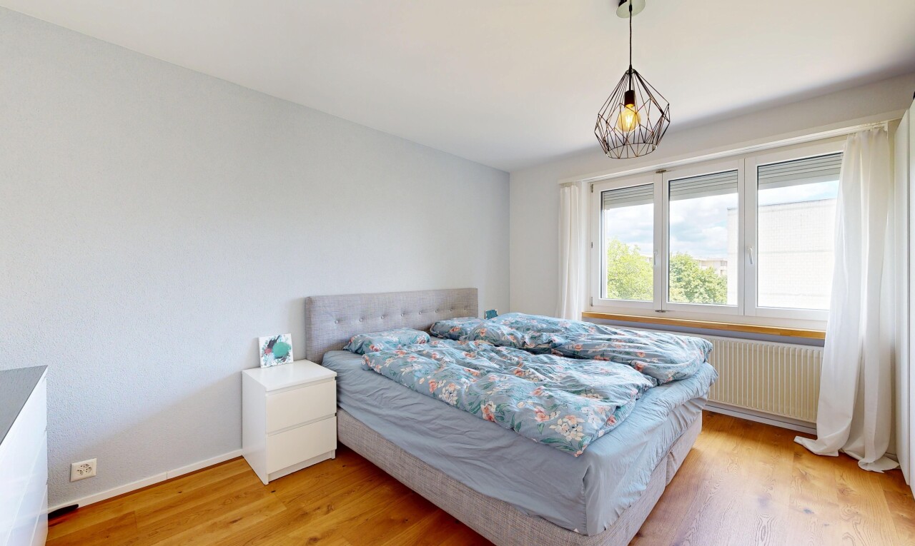 zimmer / schlafzimmer mit wood finish floor, holzfußboden, pendelleuchte, drywall, und gipskartonwand