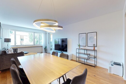 wohn- / esszimmer mit fernseher, gipskartonwand, drywall, holzfußboden, und wood finish floor