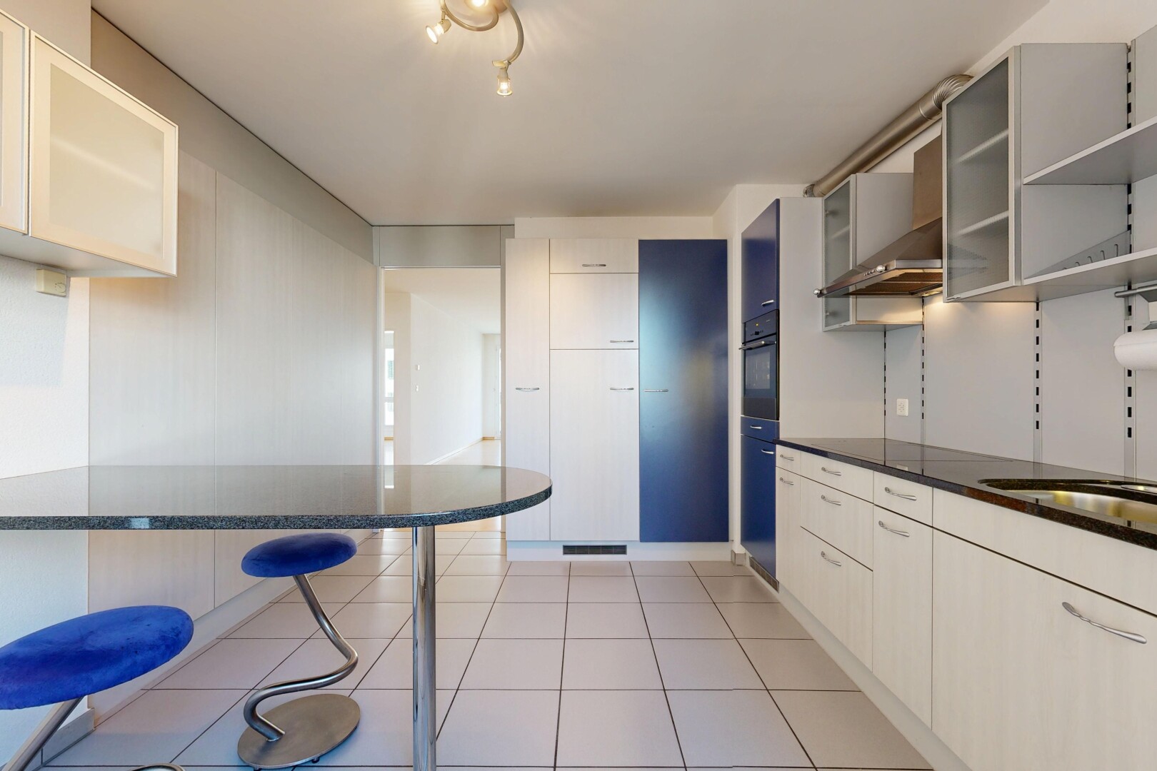 küche mit dark countertops, light floor, glass insert cabinets, schränke mit glastüren, und dunstabzugshaube