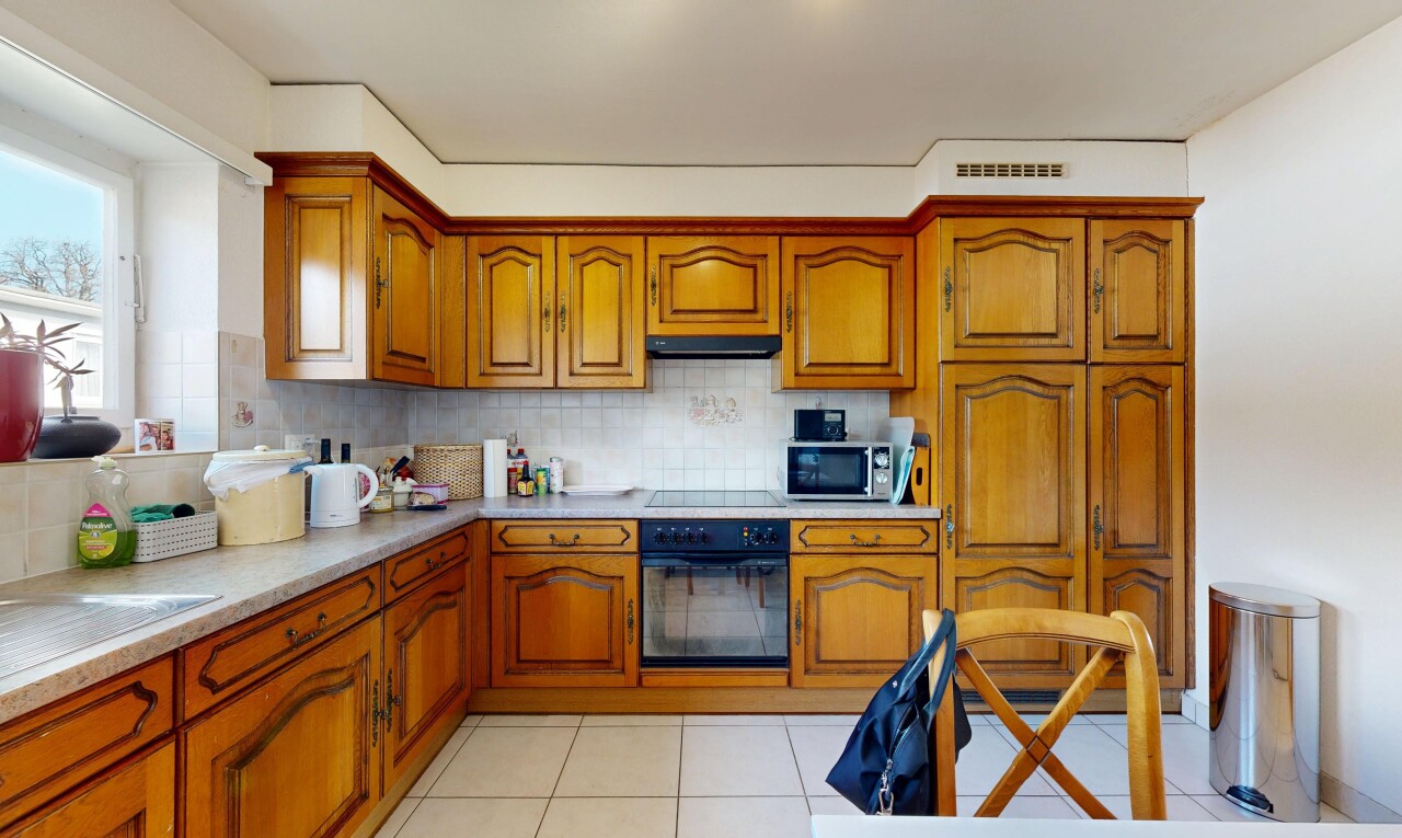 cuisine avec armoires marron moyen, medium brown cabinets, four, plans de travail, et light countertops