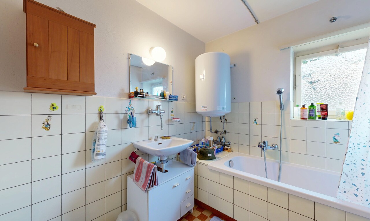 salle de bains avec miroir, chauffe-eau, salle de bain complète, inside property, et lavabo (ou coiffeuse selon le contexte)