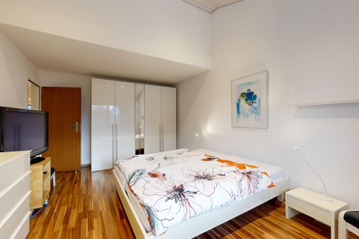 zimmer / schlafzimmer mit fernseher, wood finish floor, holzfußboden, inside property, und drywall