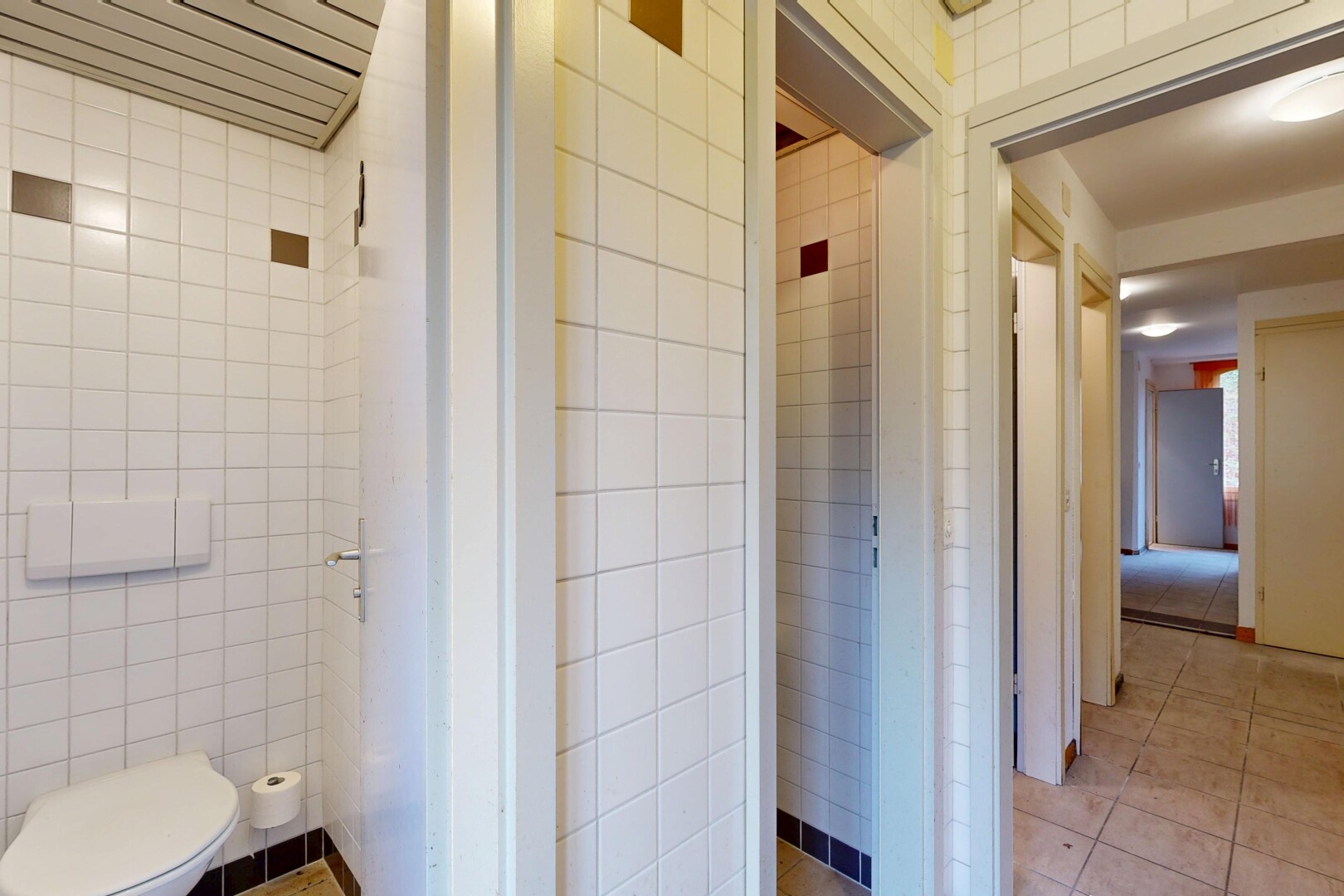 salle de bains avec tile wall, mur en carrelage, inside property, toilette, et light floor