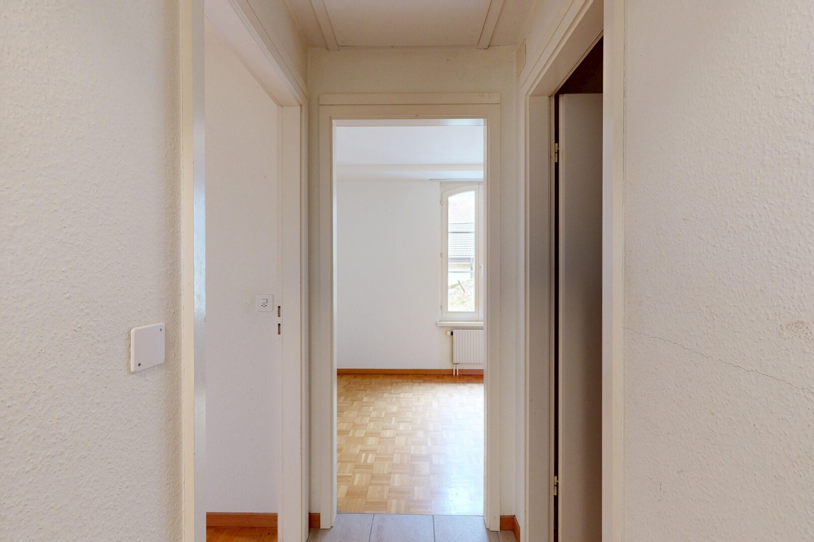 couloir avec inside property, textured wall, mur texturé, light floor, et wood finish floor