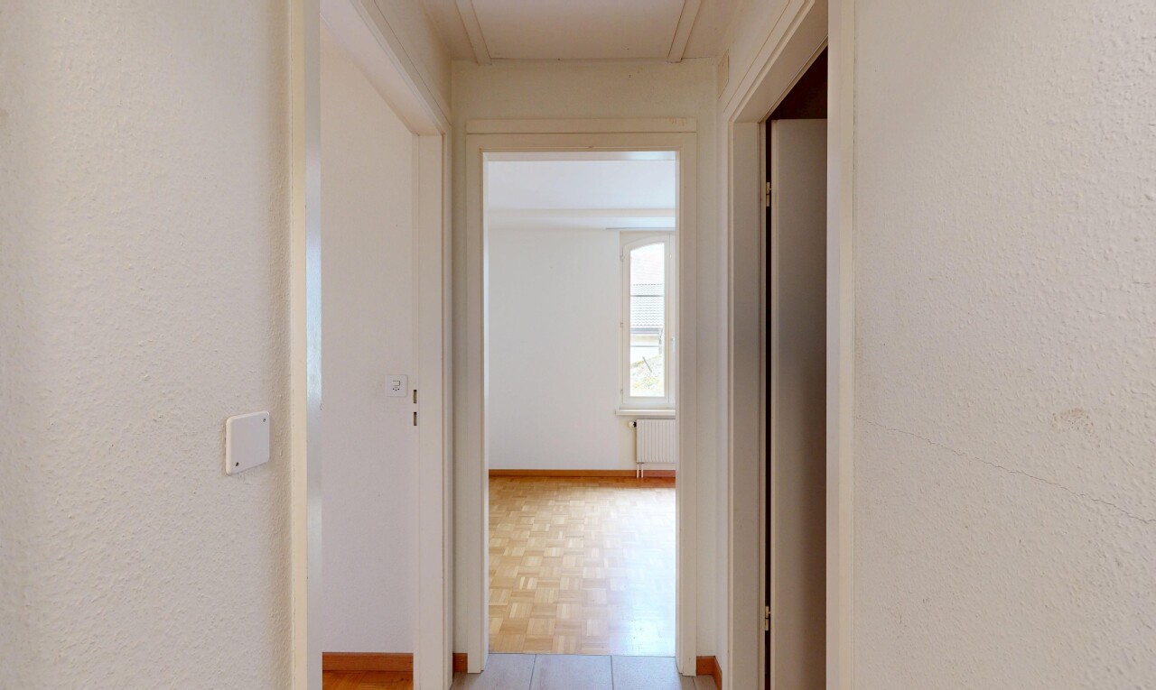 couloir avec inside property, textured wall, mur texturé, light floor, et wood finish floor