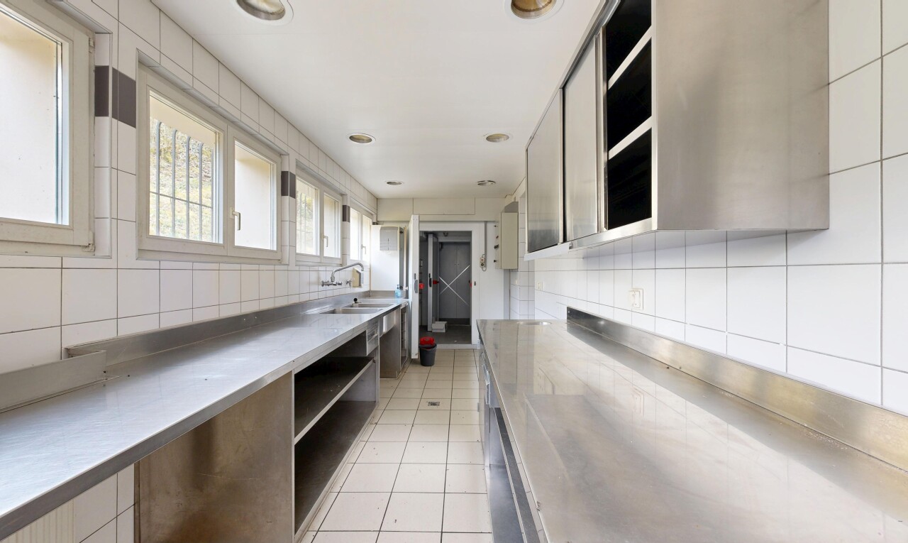 cuisine avec plans de travail en acier inoxydable, stainless steel countertops, light floor, inside property, et lumière naturelle