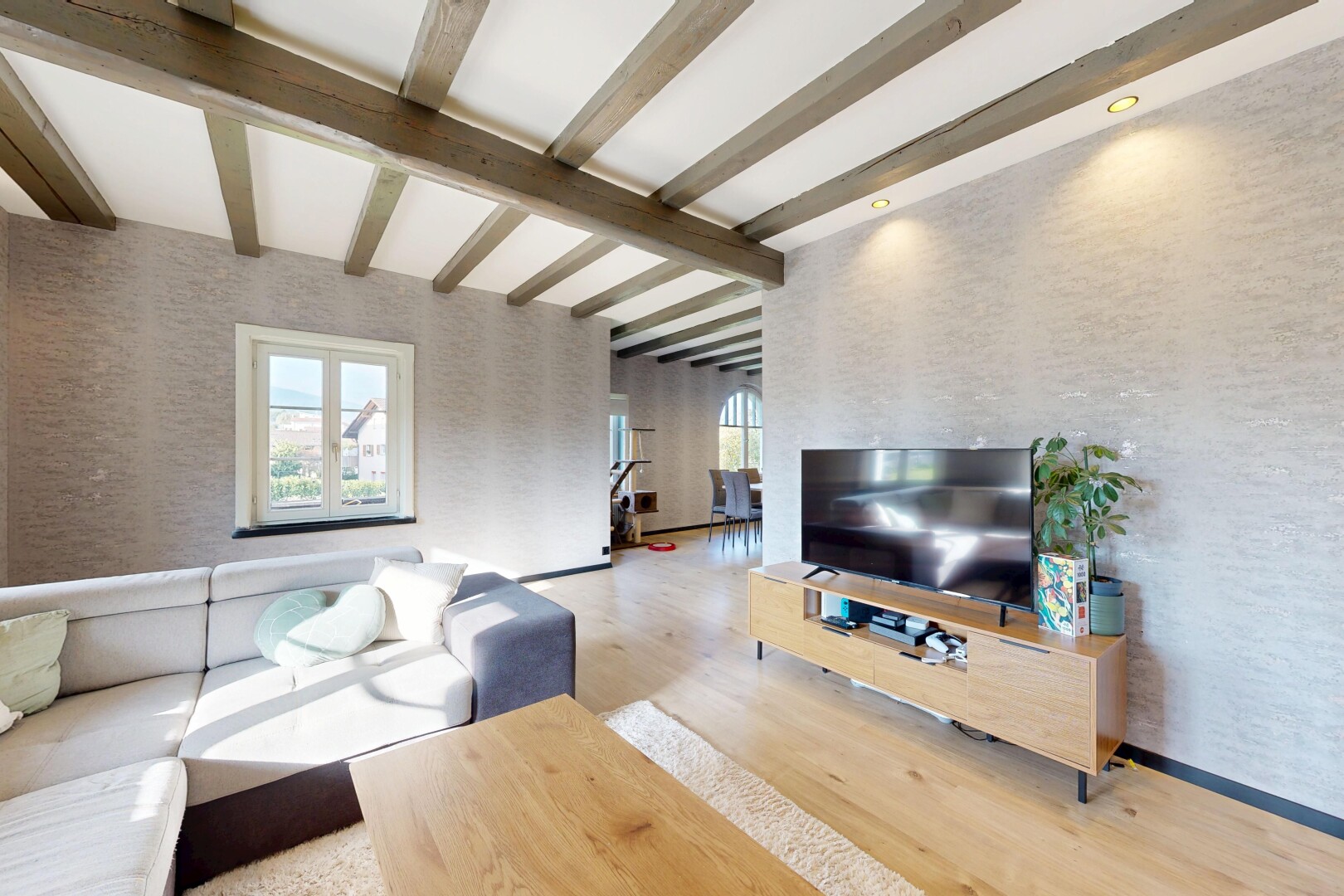 salon avec télévision, wood finish floor, sol en finition bois, inside property, et beamed ceiling