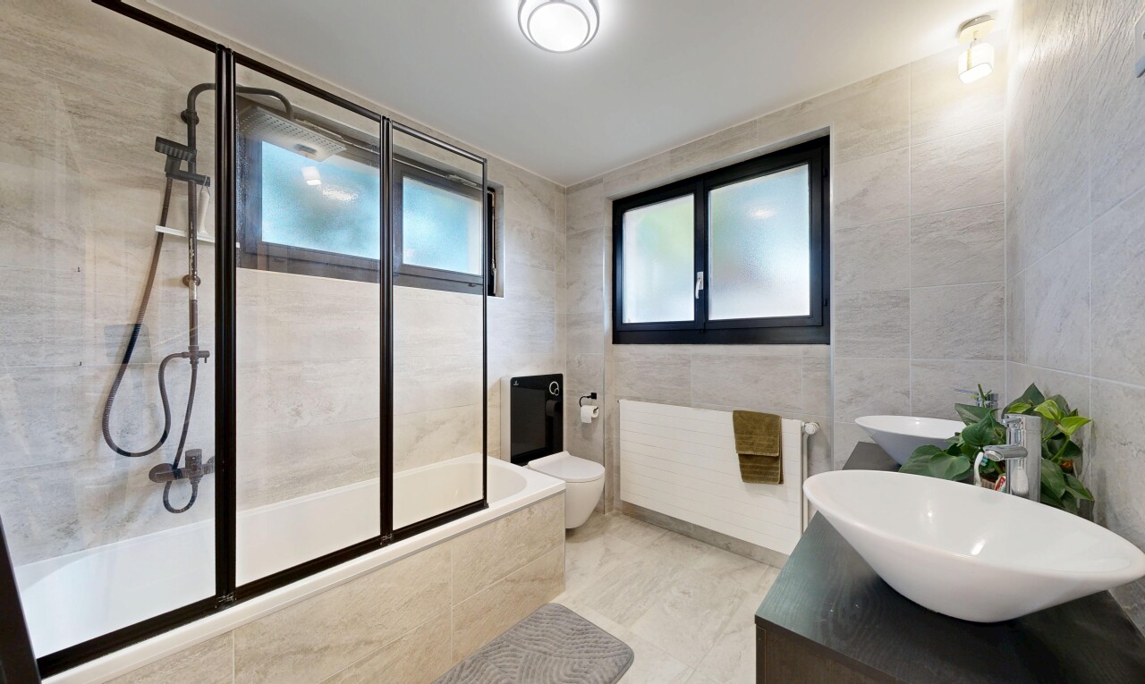 salle de bains avec mur en carrelage, tile wall, douche-bain combinés, double vasque, et salle de bain complète