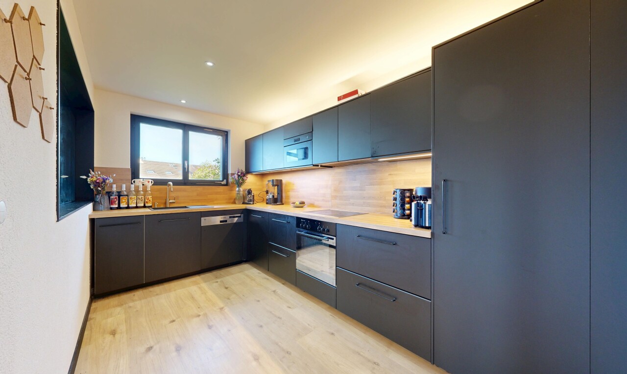 cuisine avec plans de travail, wood finish floor, sol en finition bois, armoires à panneau plat, et natural light