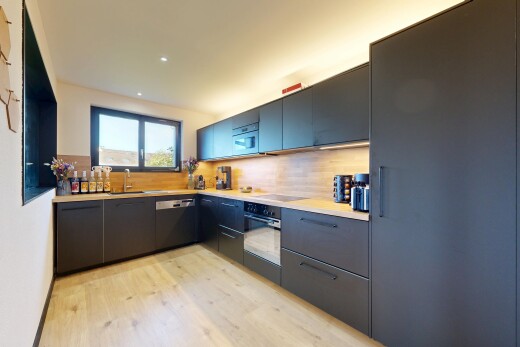 cuisine avec plans de travail, wood finish floor, sol en finition bois, armoires à panneau plat, et natural light