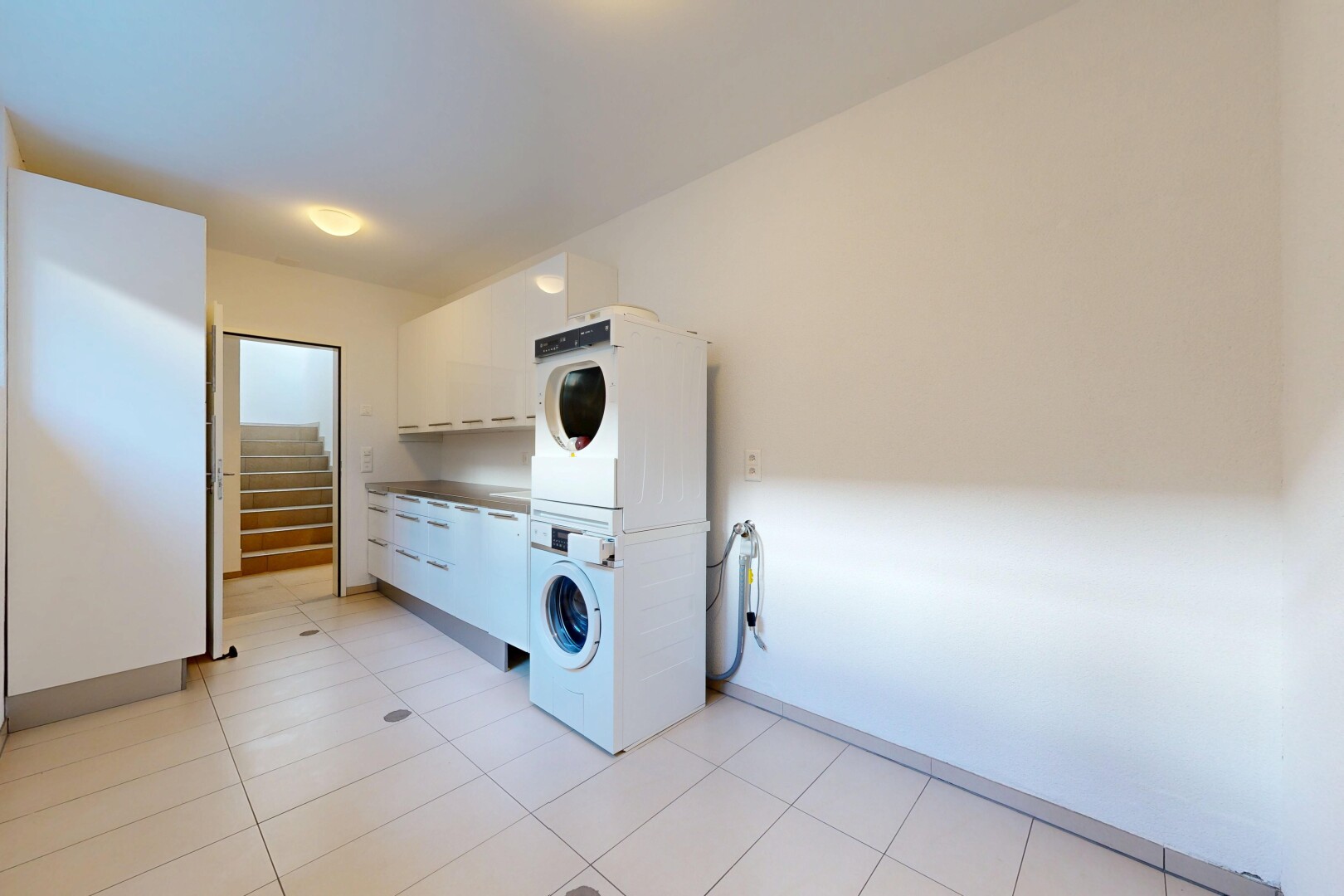 laundry room featuring stacked washer and dryer and light tile patterned floors