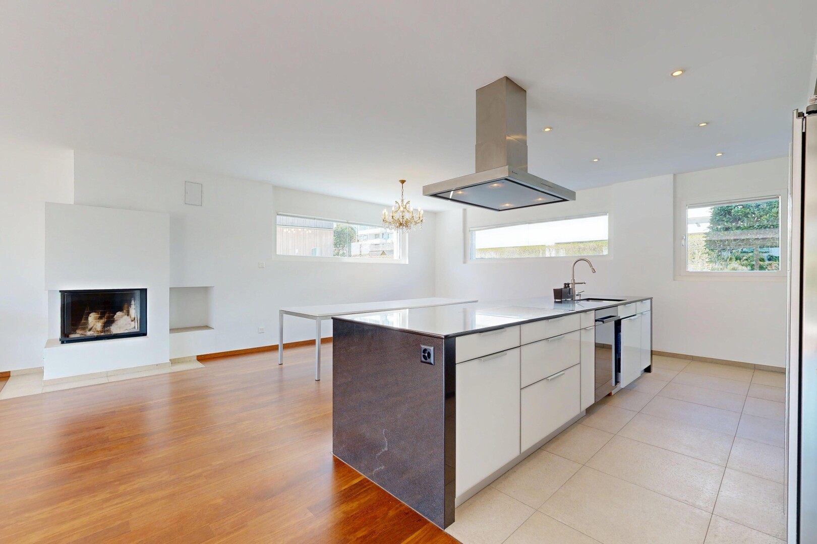 kitchen featuring island range hood, white cabinetry, light countertops, a glass covered fireplace, and open floor plan