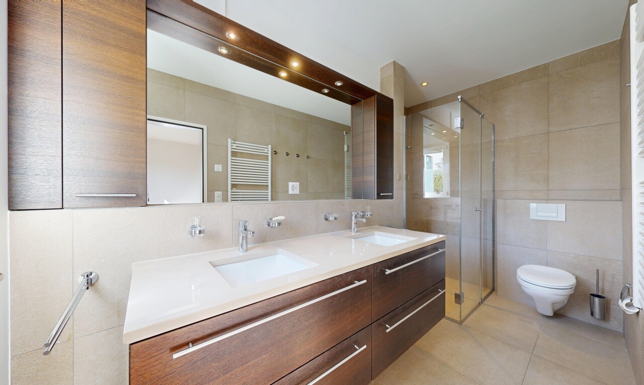 bathroom with tile walls, a stall shower, double vanity, a towel warmer, and radiator