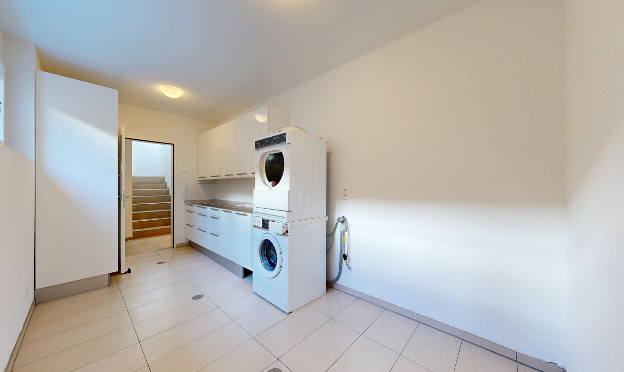 laundry room featuring stacked washer and dryer and light tile patterned floors