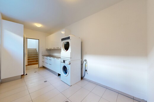 laundry room featuring stacked washer and dryer and light tile patterned floors
