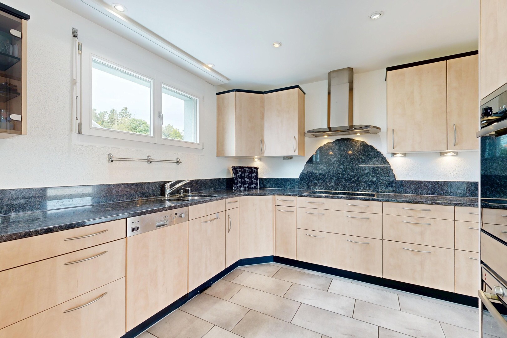 küche mit hellbraune schränke, natürliches licht, natural light, dunstabzugshaube, und stein arbeitsplatten