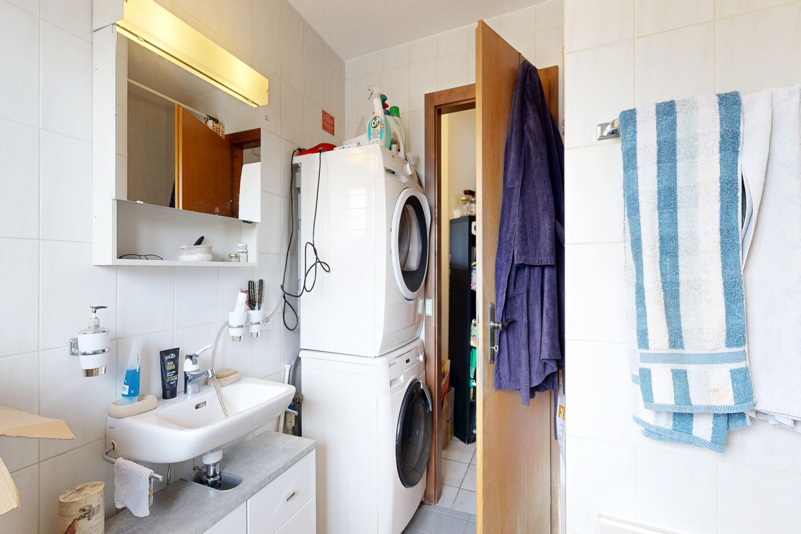 buanderie avec tile wall, mur en carrelage, buanderie, inside property, et lave-linge et sèche-linge superposés