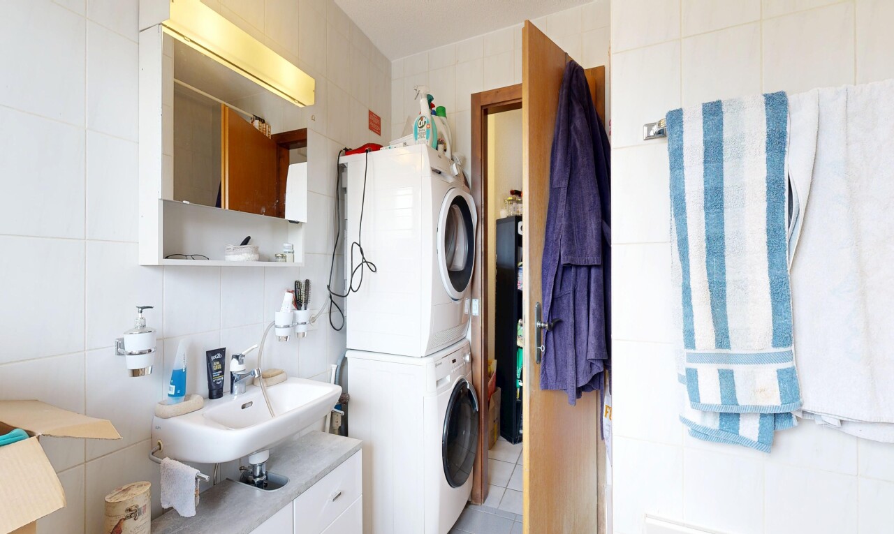 buanderie avec tile wall, mur en carrelage, buanderie, inside property, et lave-linge et sèche-linge superposés