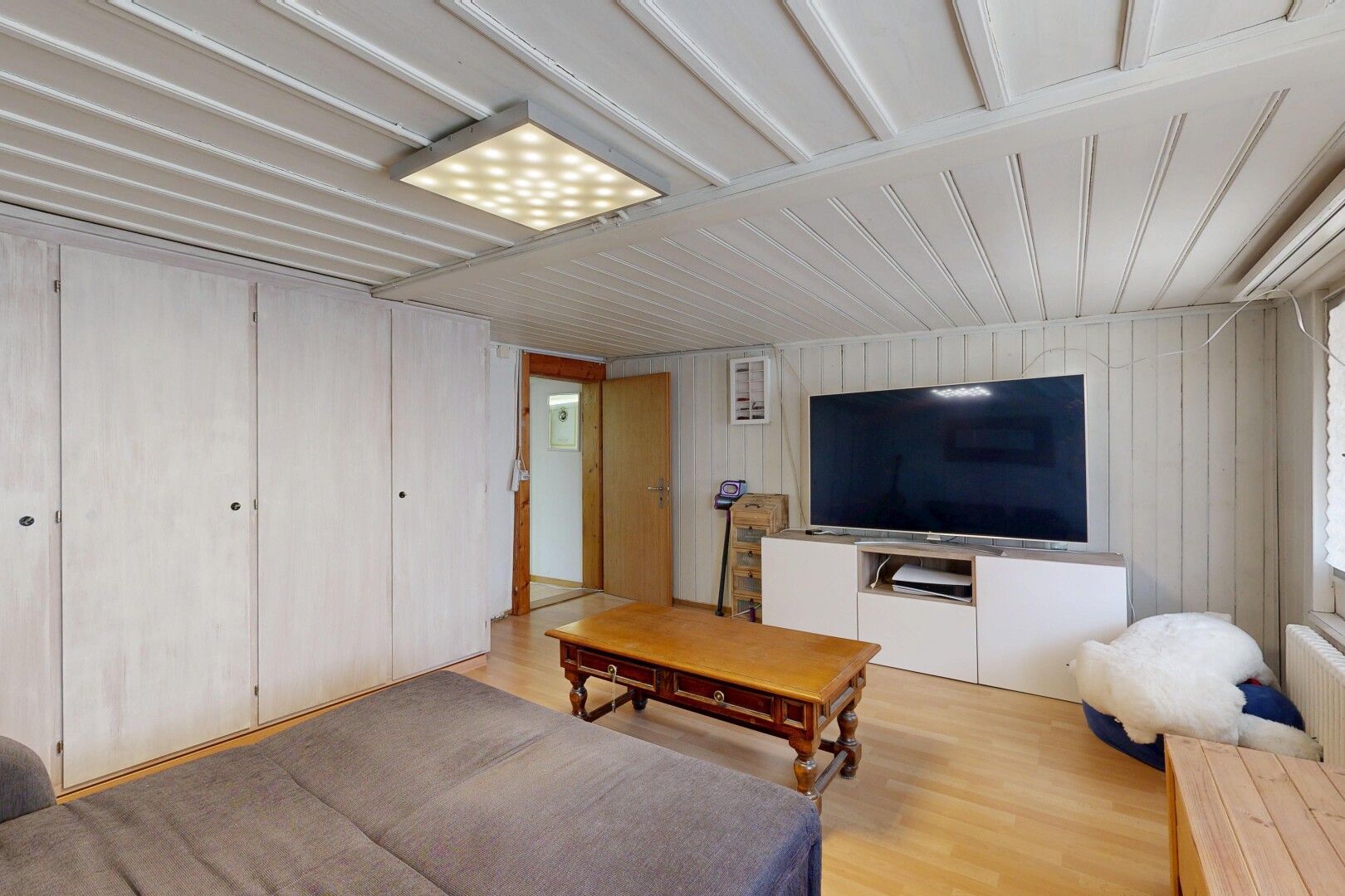 wohnzimmer mit wood finish floor, holzfußboden, fernseher, wood wall, und holzwand