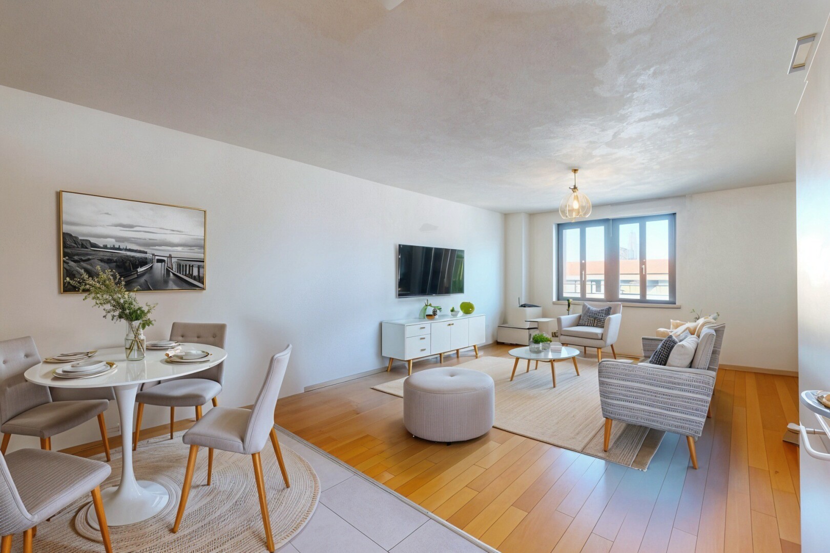 salon / salle à manger avec lumière naturelle, télévision, cloison sèche, et sol en finition bois