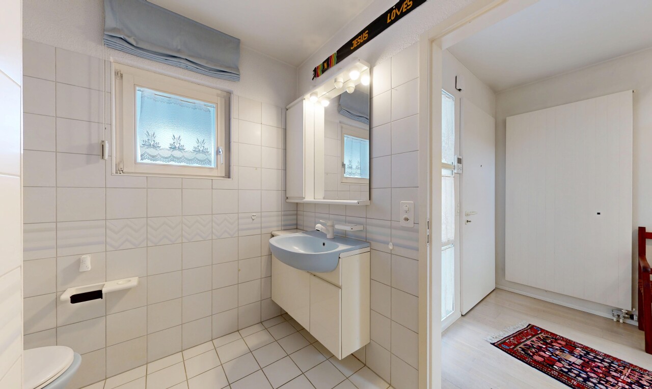 salle de bains avec lavabo (ou coiffeuse selon le contexte), mur en carrelage, tile wall, toilette, et miroir