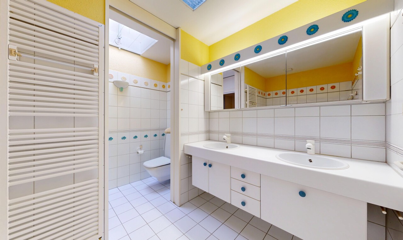 salle de bains avec radiateur, double vasque, puits de lumière, inside property, et mur en carrelage